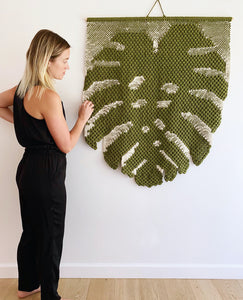 Meg with a green, monstera-shaped tapestry