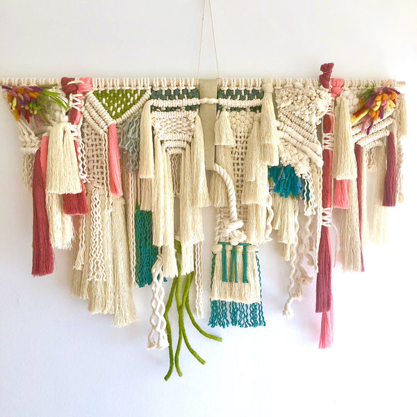 A cream-based tapestry with green, teal, and pink accents
